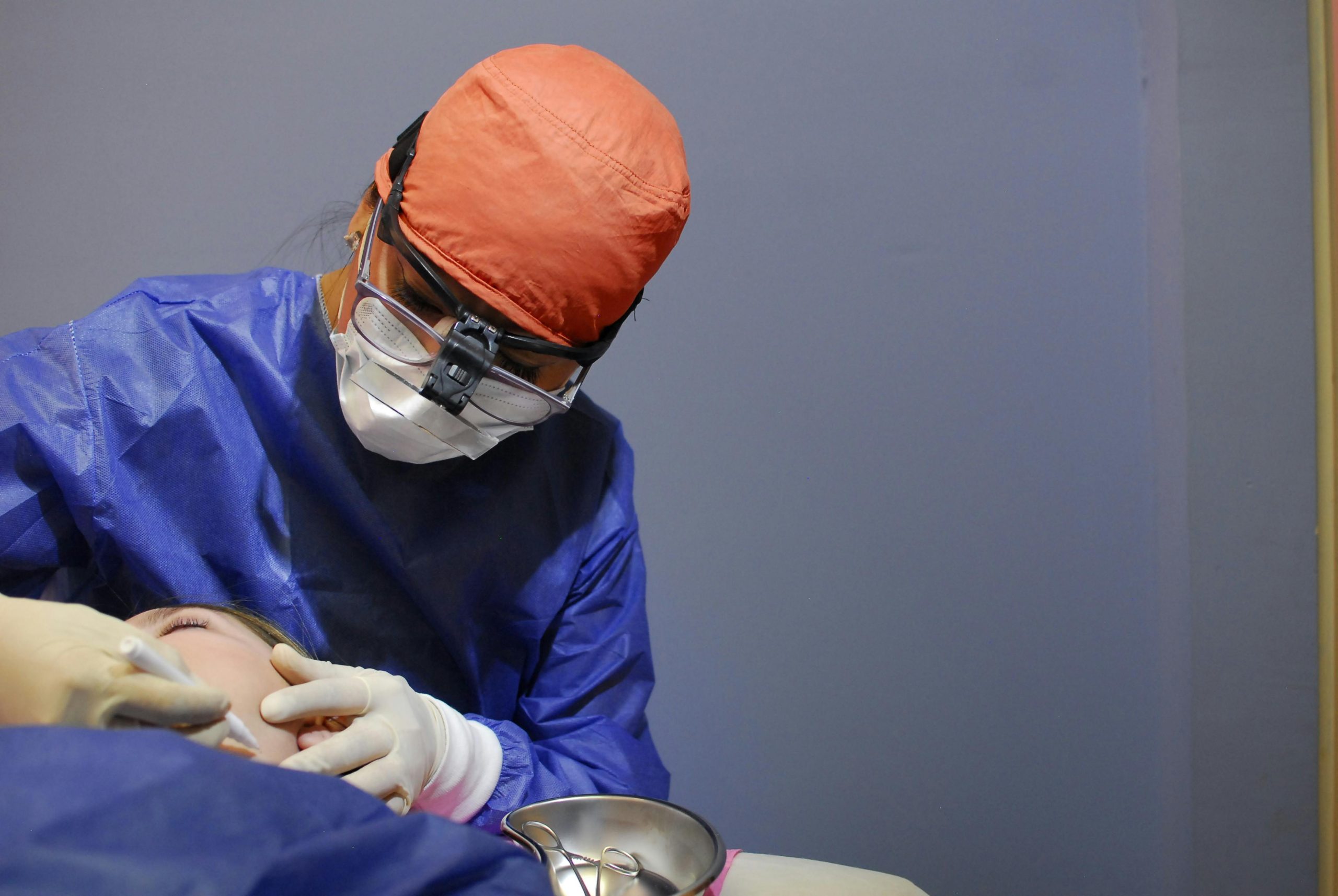 Dentist in protective gear performing a procedure in a hospital setting for safety and healthcare.